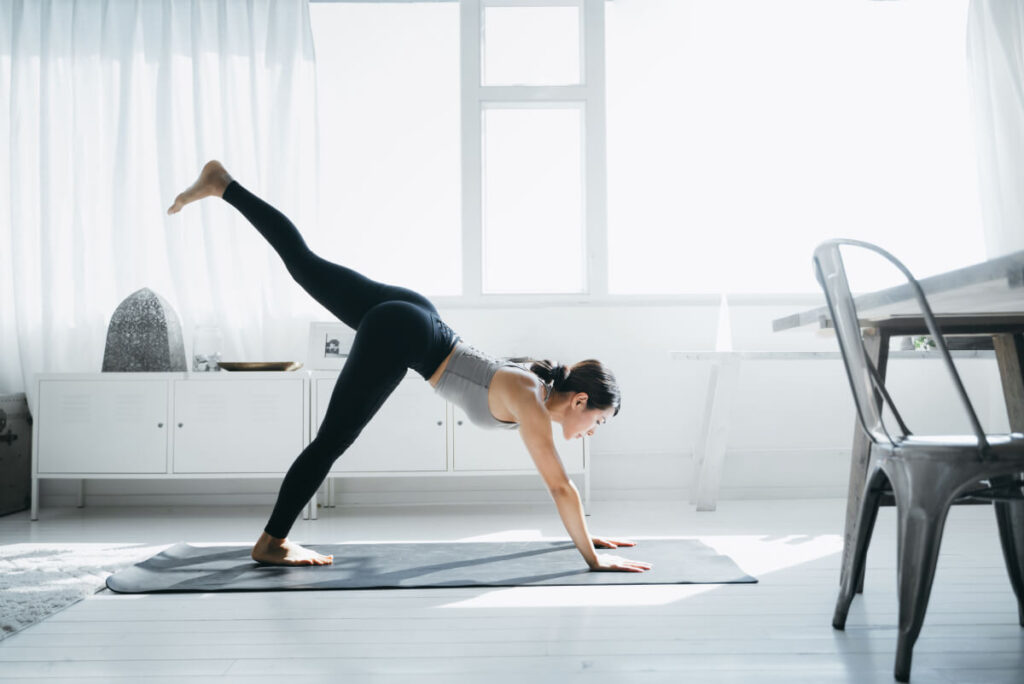 Young Asian woman practicing yoga in the living room at home