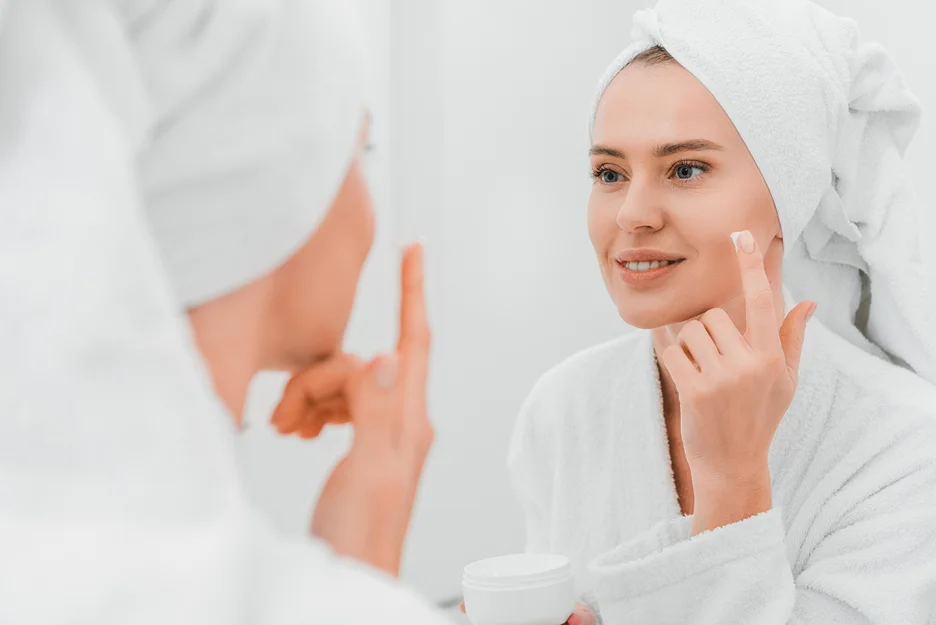 a woman applies moisturizer on her face after polynucleotide treatment