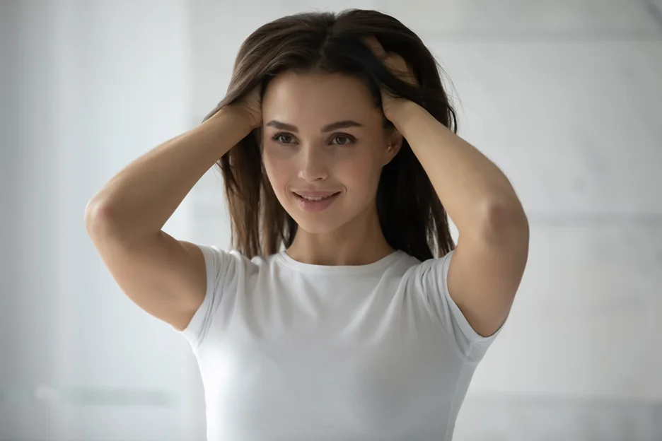 a portrait of a woman standing by the mirror while touching her hair
